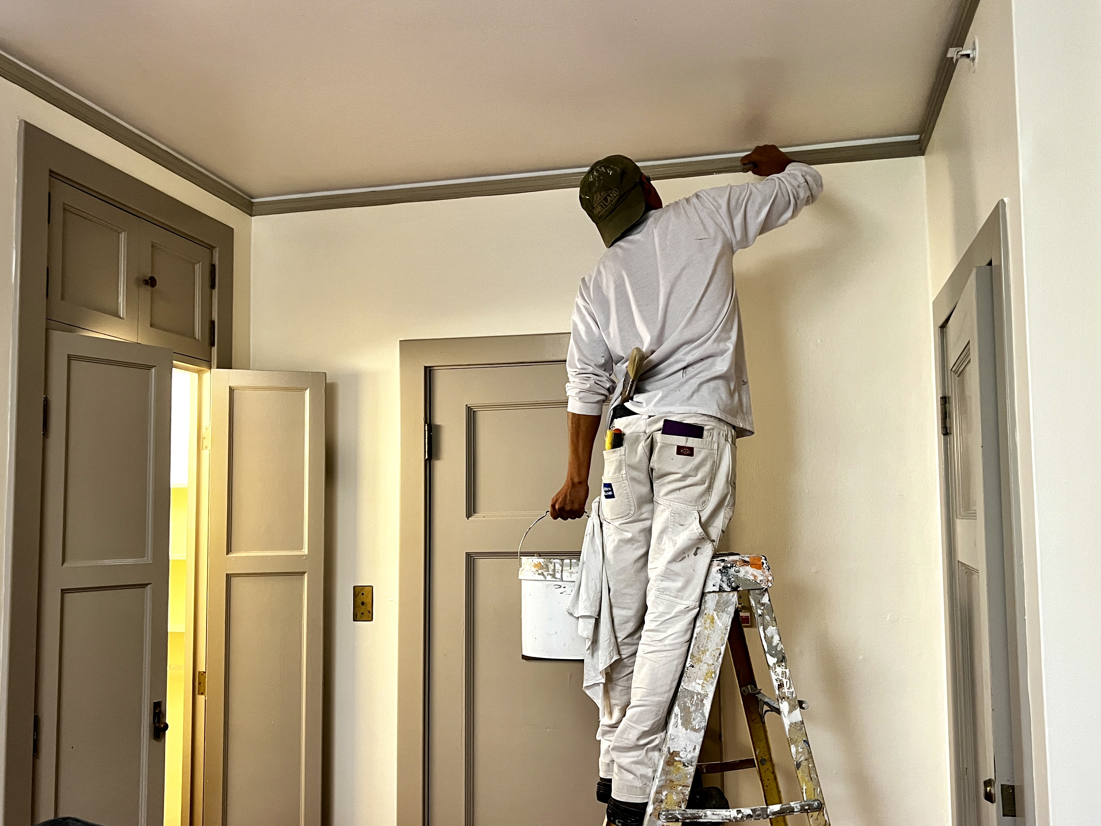 Chay & Harris painter cutting in crown molding on a ladder