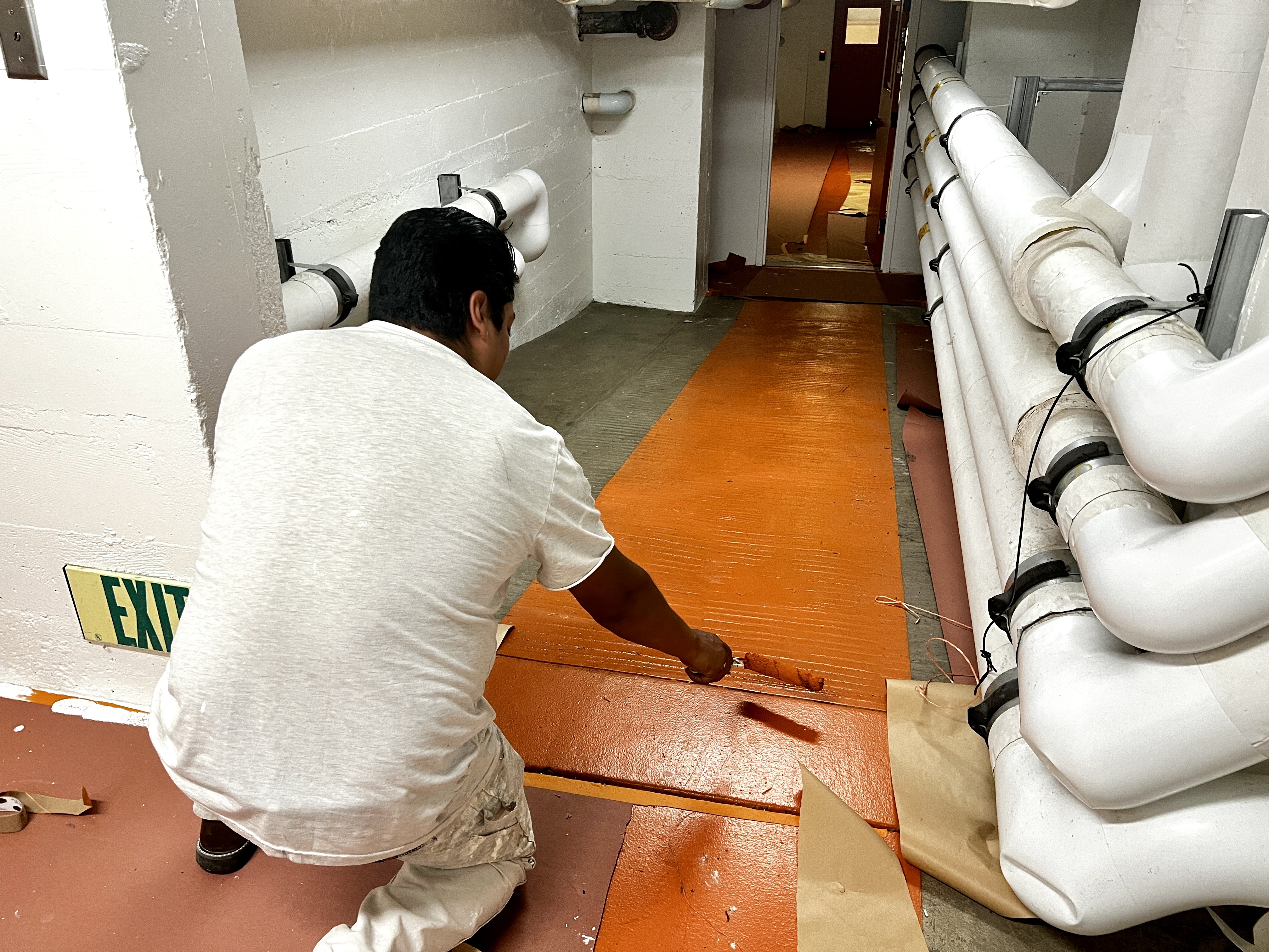 Chay & Harris painter applying epoxy floor coating in mechanical corridor
